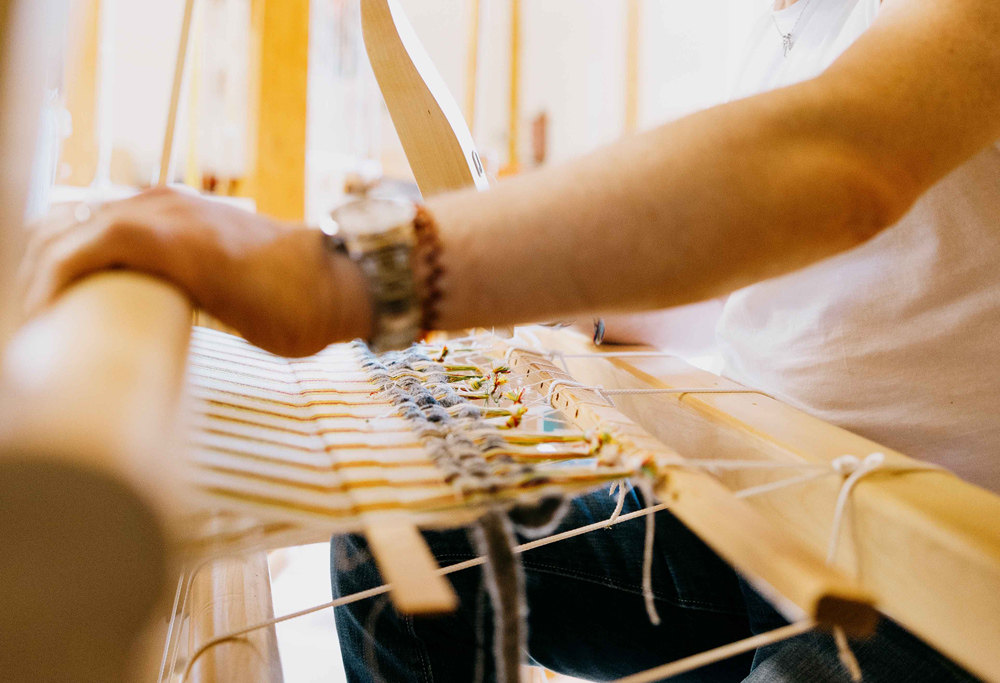 Mann arbeitet am Webstuhl