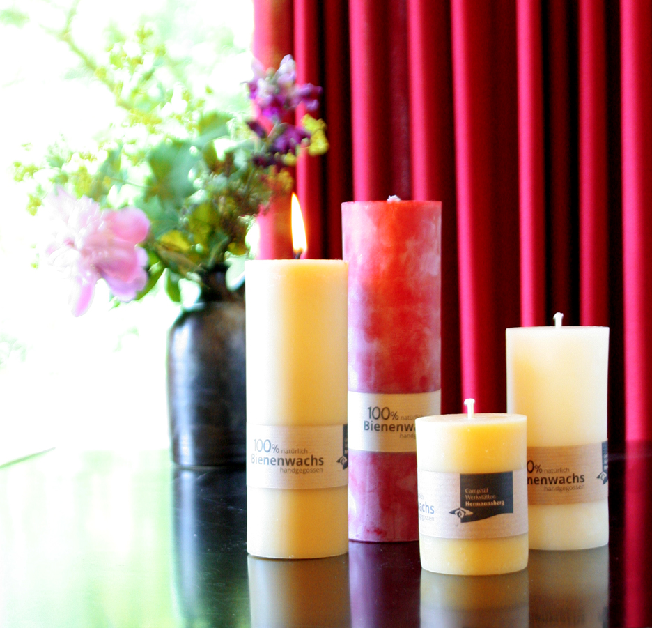 Stumpenkerzen in verschiedenen Farben und Größen als Dekobeispiel mit Blume