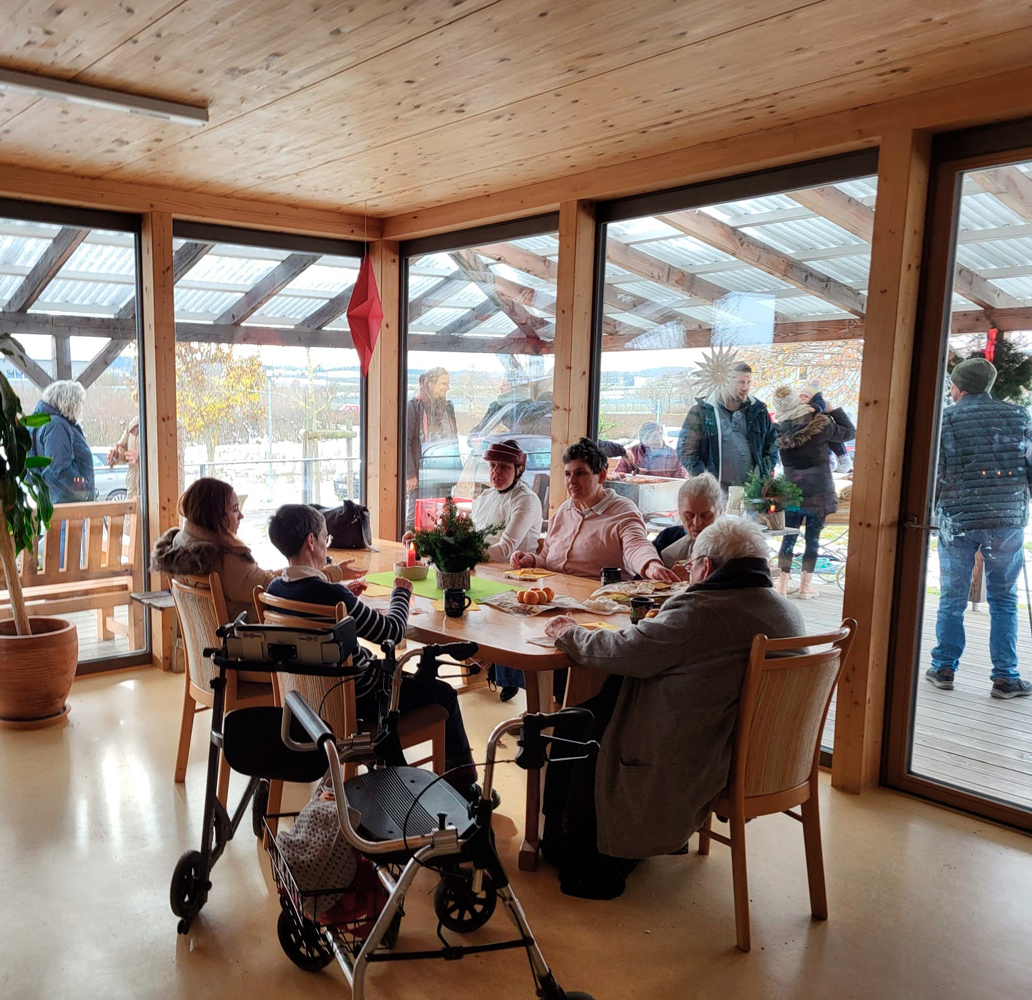 Personen sitzen am Tisch bei Kaffee und Kuchen Personen sitzen am Tisch bei Kaffee und Kuchen