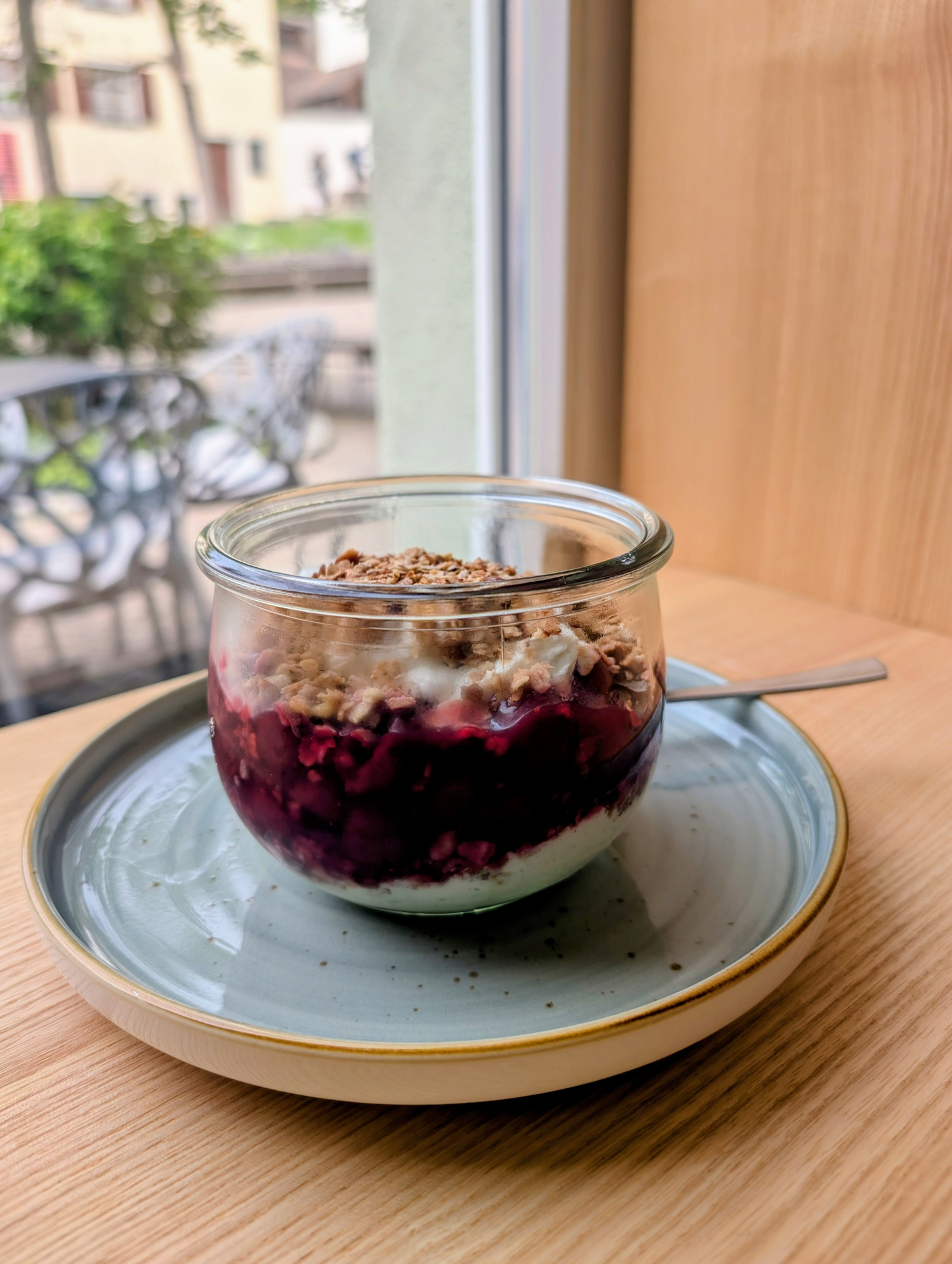 Ein Glas Quark mit Himbeeren und Granola